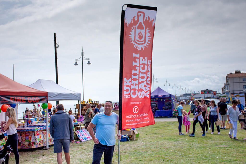 Photograph of Jason Oliver, Chilli Festival owner with a branded feather flag