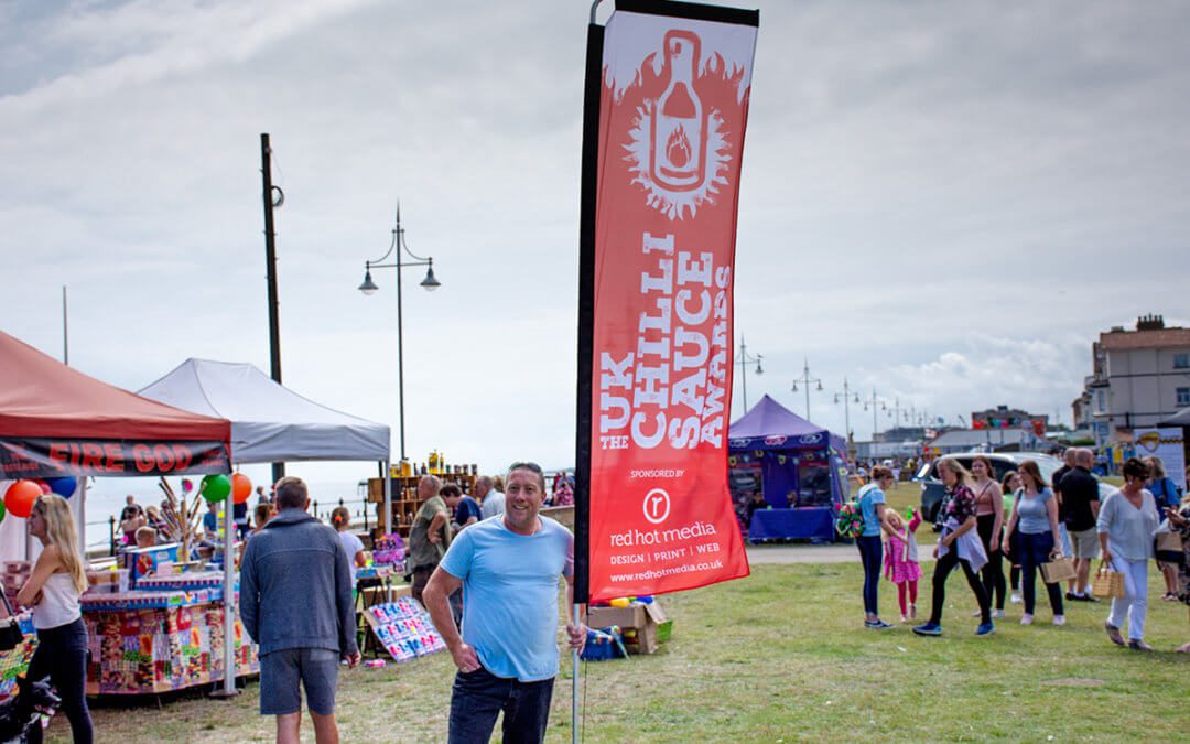 Photograph of Jason Oliver, Chilli Festival owner with a branded feather flag