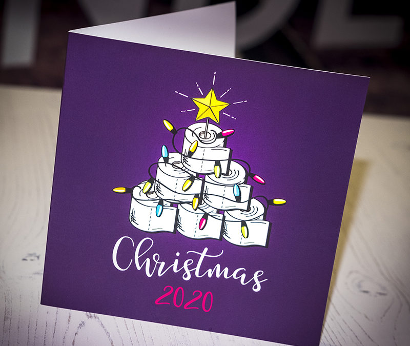 Photograph of a square shaped Christmas Card with an illustration of toilet rolls stacked in the shape of a Christmas Tree with a string of coloured Christmas lights and a yellow star on top