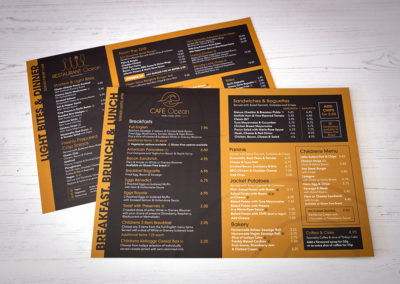 Photograph of an A4 Cafe Ocean food menu laying on white wooden floorboards